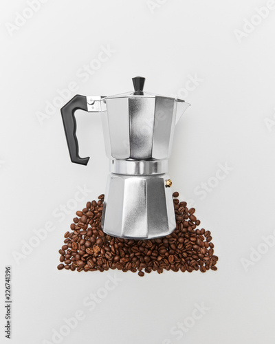 The pattern of coffee beans and a metal coffee maker on a gray background with space for text. Concept of morning coffee. Flat lay