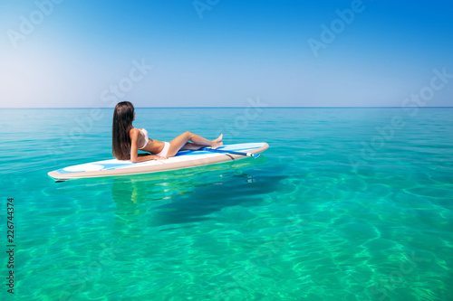 Beautiful woman on the Standup paddlbording relaxing in the sea with clean water. Leisure activities in the tropical ocean islands on surf.