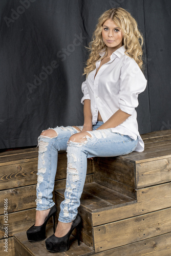 Young beautiful girl blonde in a white shirt and jeans with gaps 