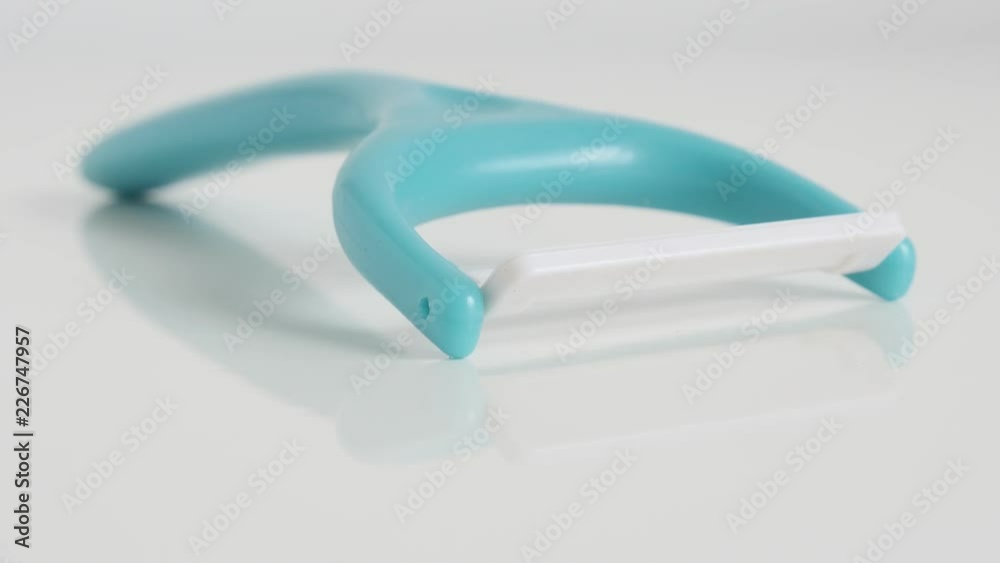 Blue vegetable peeler on white background close-up 4K tilting video Blue vegetable peeler on white background close-up 4K tilting video