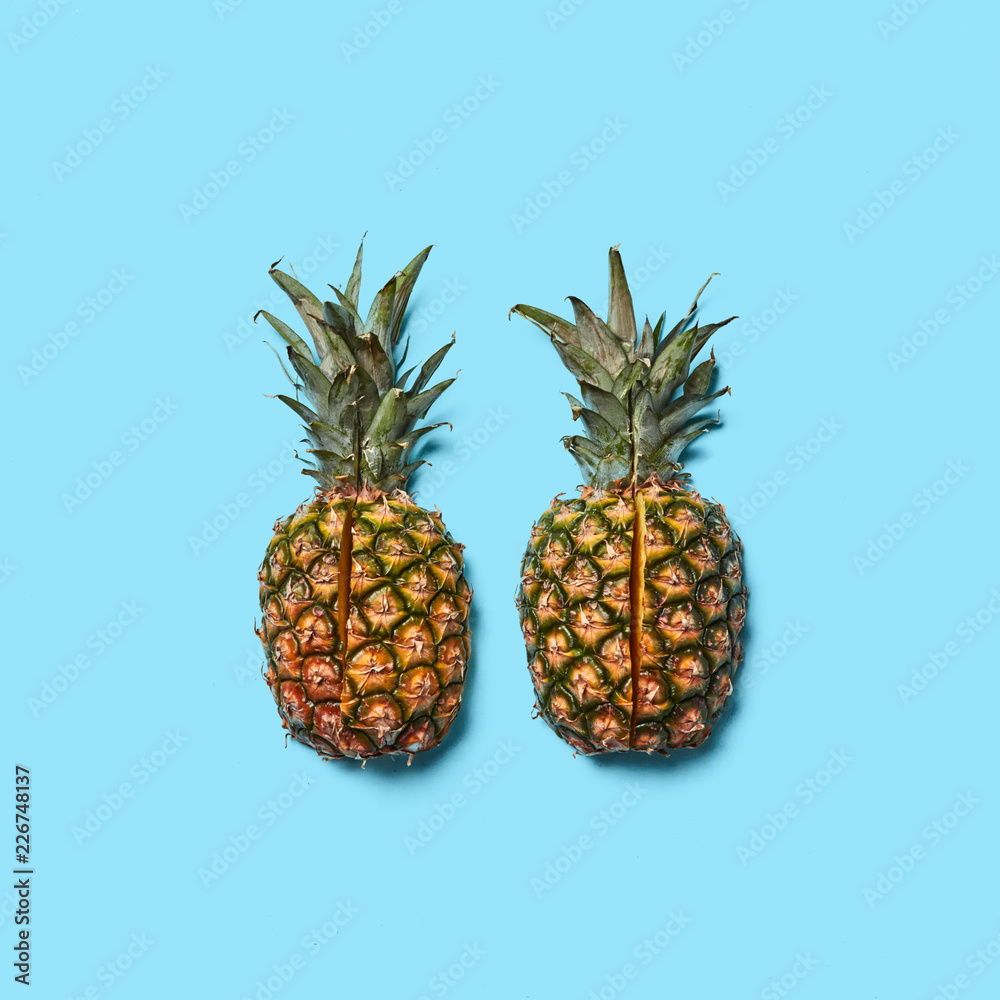 Pineapple with green leaves cut into pieces presented on a blue background with space for text. Creative layout for your ideas. Flat lay
