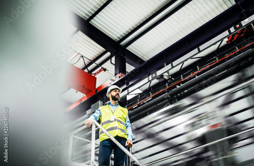 A low angle view of an industrial man engineer standing in a factory. photo