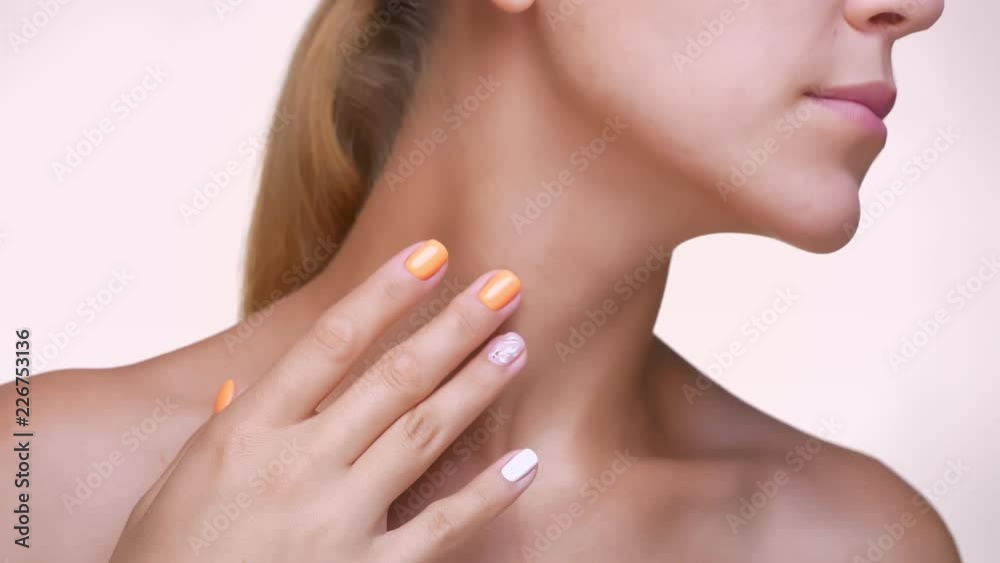 Gorgeous caucasian female is stroking her face and neck with healthy clear skin, looking aside in white studio Gorgeous caucasian female is stroking her face and neck with healthy clear skin, looking aside in white studio