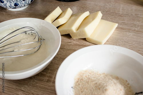 Pieces of cheese eidam and  bowls  - preparation for wrapping and frying photo