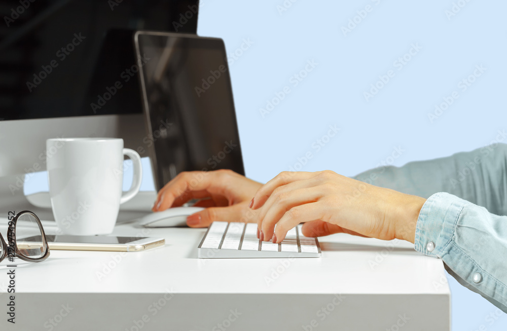 Young woman sitting at the table with open netbook computer. Female person using modern technology.