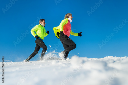 Senior couple runners running in winter nature. Copy space.