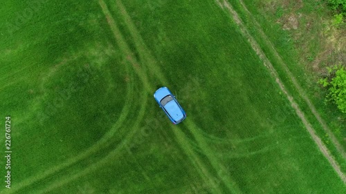 Blue car on green field earial view move top photo