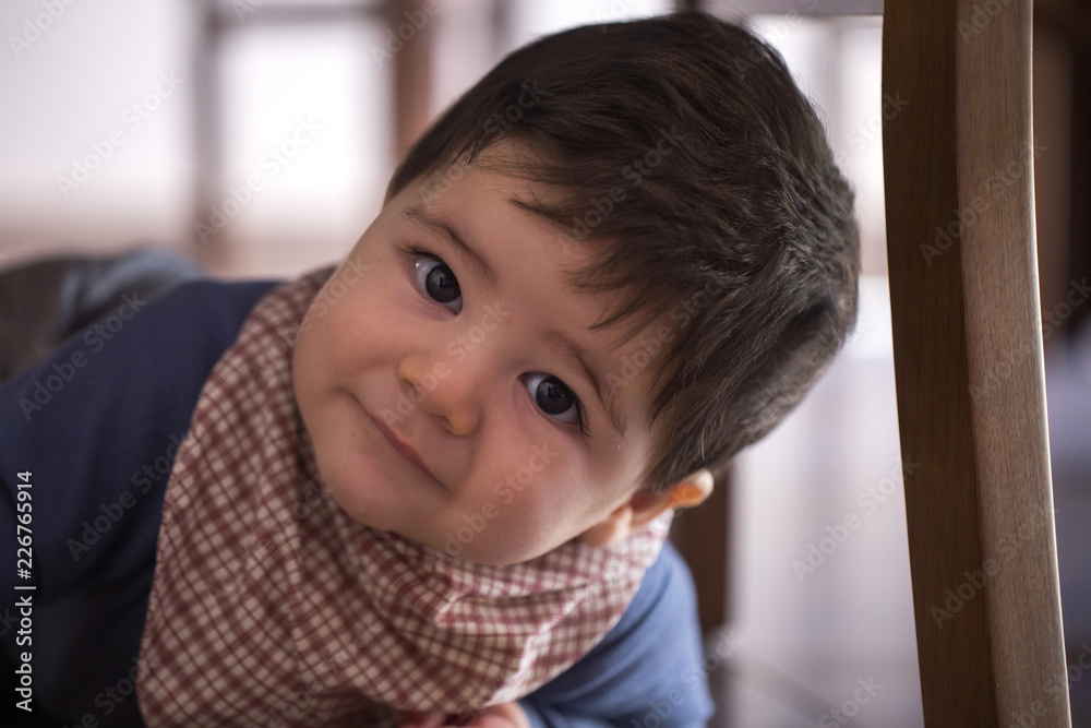 Cute baby boy under the table looking at the camera Cute baby boy under the table looking at the camera
