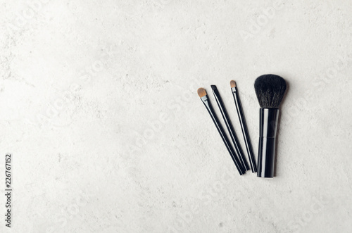 Black makeup brushes on a light stone background. Professional tools for make-up artist. Flat Lay  top view  copy space.