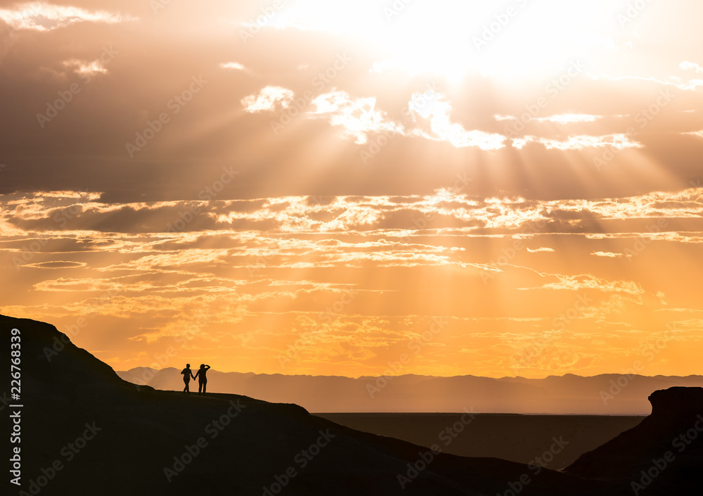 Romantic Couple holding hands, romance Sunset with sun ray burst over flaming cliffs in Mongolia