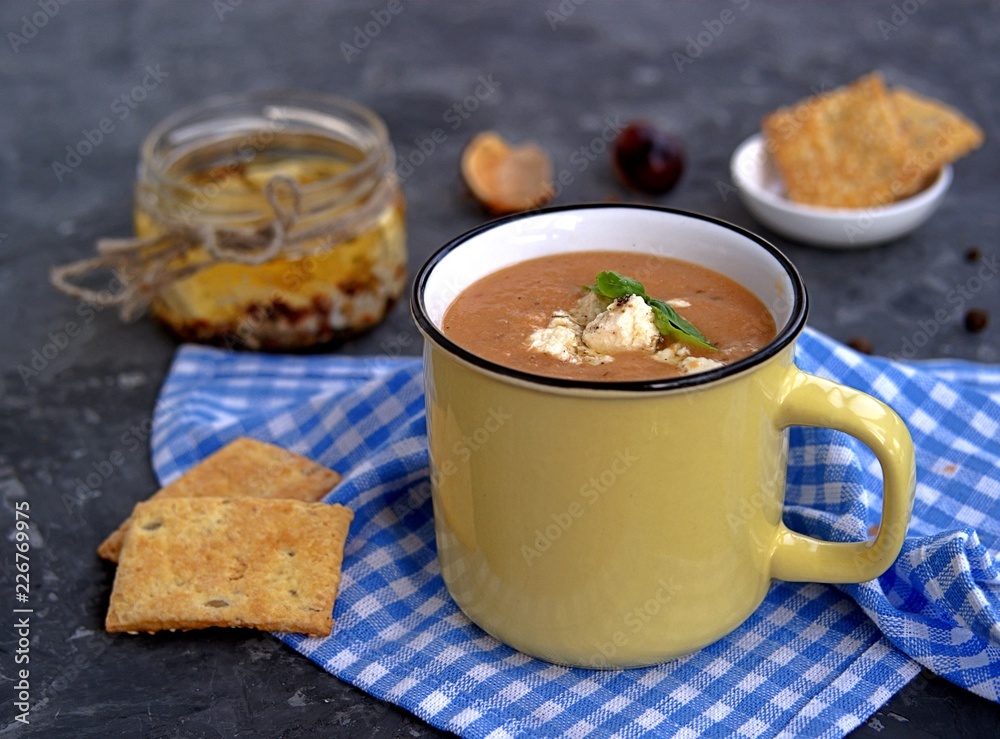 Soup puree from baked aubergines and tomatoes in a yellow mug. Served with feta cheese and crackers. Soup puree from baked aubergines and tomatoes in a yellow mug. Served with feta cheese and crackers.