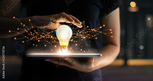 Innovation. Hands holding tablet with light bulb future technologies and network connection on virtual interface background, innovative technology in science and communication concept .
