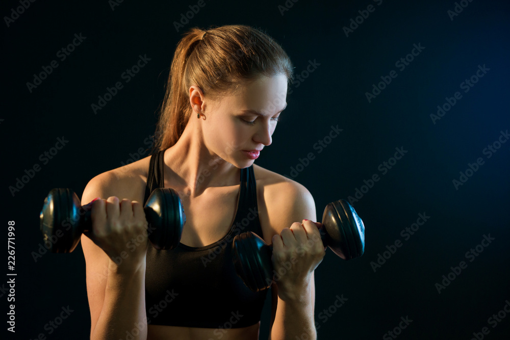 beautiful young girl goes in for sports with dumbbells on a black background beautiful young girl goes in for sports with dumbbells on a black background