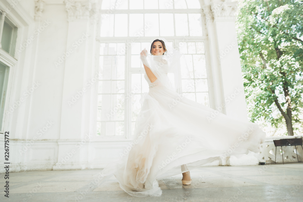 Beautiful bride in wedding dress with long full skirt, white background, dance and smile Beautiful bride in wedding dress with long full skirt, white background, dance and smile