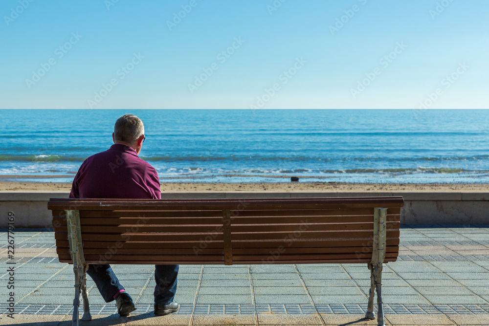 Man på en parkbänk vid havet