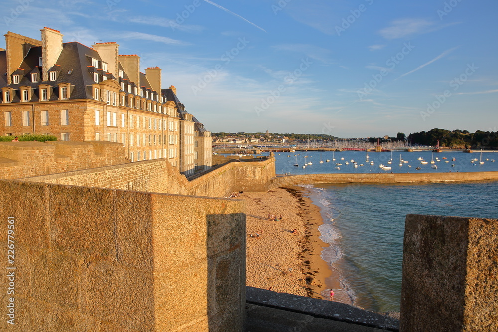 The ramparts of the walled city of Saint Malo at sunset, with the Mole beach and the harbor in the background, Saint Malo, Brittany, France