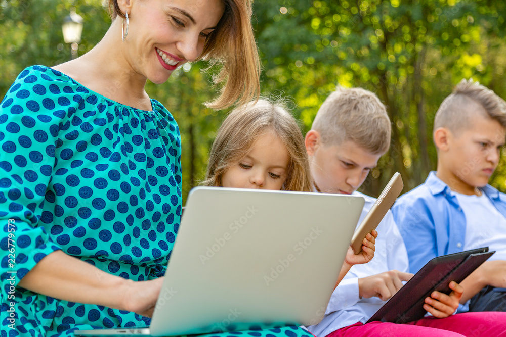 Young family with gadgets sitting on the bench Young family with gadgets sitting on the bench