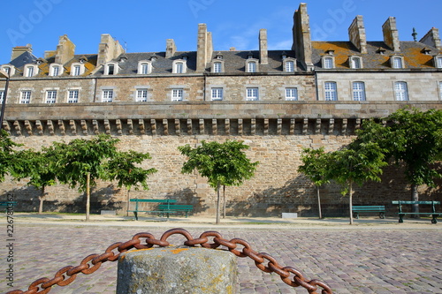 View of Traditional houses with chimneys inside the walled city of Saint Malo, with the cobbled pavement of Robert Surcouf Esplanade in the foreground, Saint Malo, Brittany, France