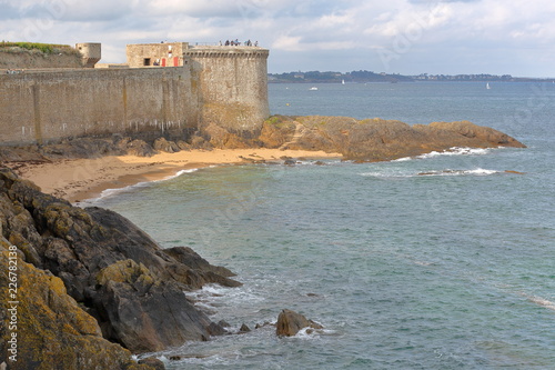 View of the Bidouane Tower, located along the ramparts inside the walled city of Saint Malo, Brittany, France, with the rocky coast in the foreground