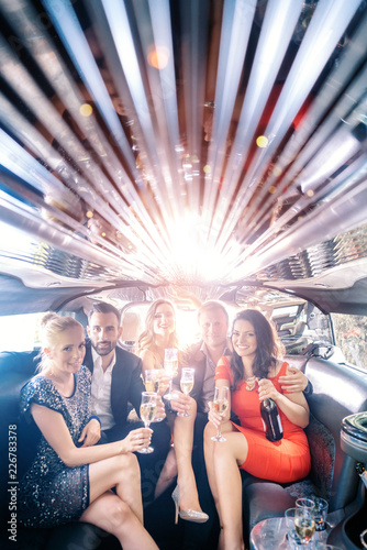 Wall Mural Celebration in a limo, woman and men drinking champagne and having a party