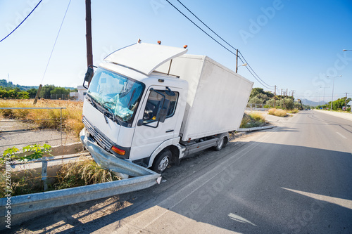 Crashed truck that hit crashed barrier on road, broken windshield, sunny day