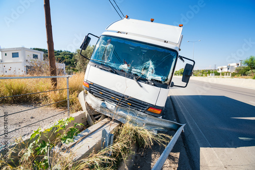 Front of crashed truck that hit crashed barrier on the road, broken windshield, sunny day