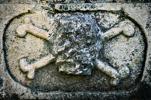 Ancient sculpture of a skull with crossed bones on a tomb in russian Joseph-Volotsky monastery