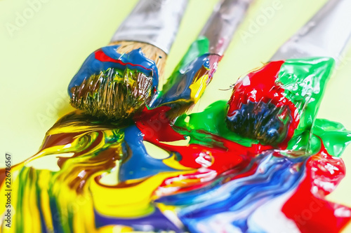 acrylic paint and artistic brush squeezed out against a yellow background, close-up,