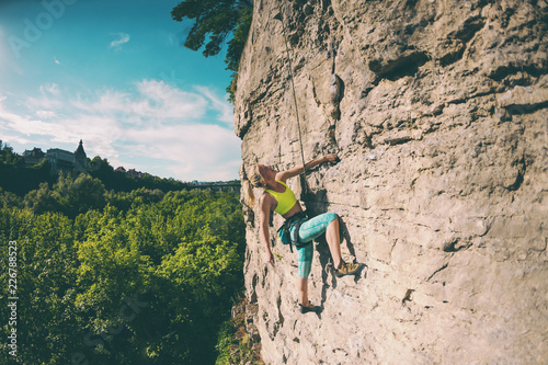 The woman climbs the rock.