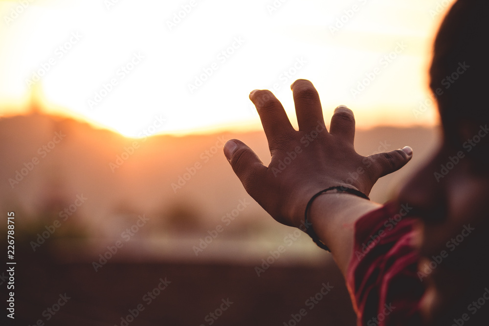 Hand reaching out for sunset