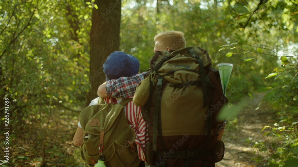Young couple enjoying summer forest during hiking with backpacks in national park