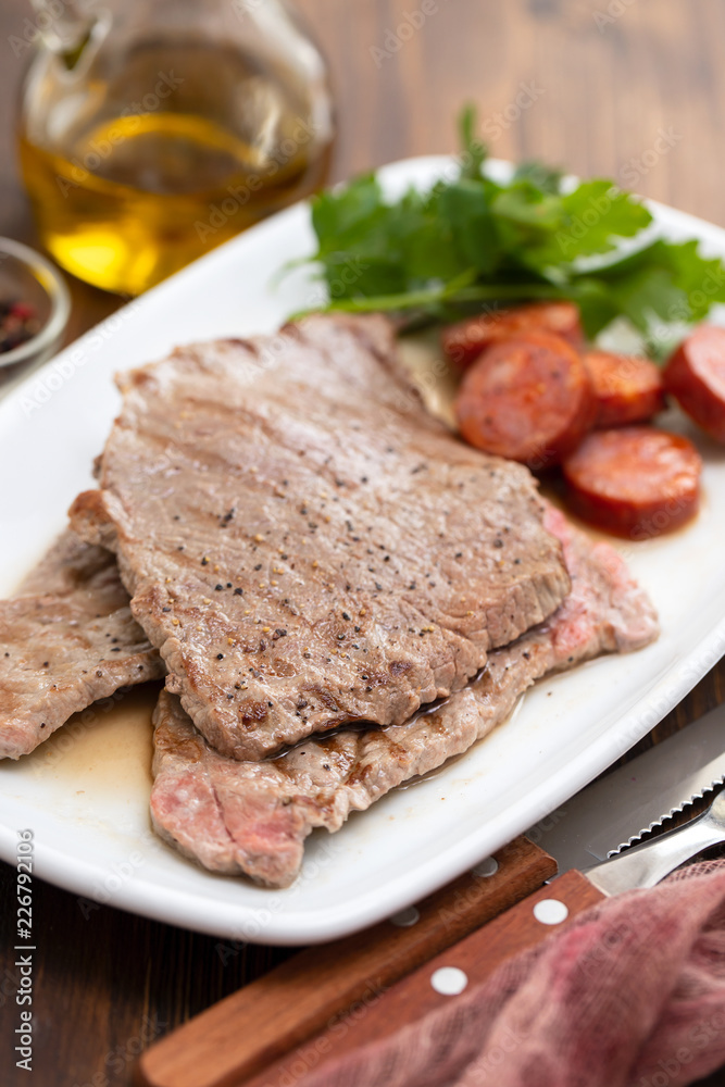 grilled meat with smoked sausage on white dish grilled meat with smoked sausage on white dish