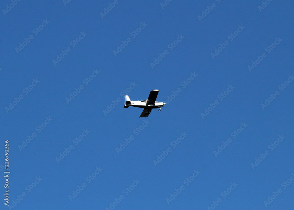 white airplane flies in the blue sky over the river and rolls people. white airplane flies in the blue sky over the river and rolls people.