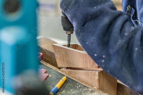 Eco friendly woodworker's shop. Details and focus on the texture of the materials, saw dust, and blocks, while making a designer coffee table with a drilling machine. Cnc woodery tools. photo