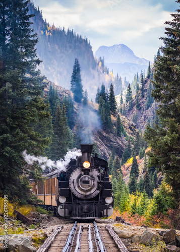 Fotografie Steam Train Crossing a Trestle Bridge in the Mountains
