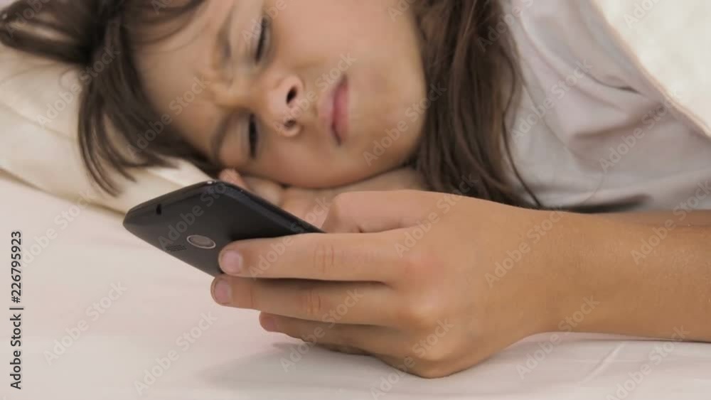 Alarm clock on the phone. Awakening a child. Little girl woke alarm clock on the phone. Alarm clock on the phone. Awakening a child. Little girl woke alarm clock on the phone.