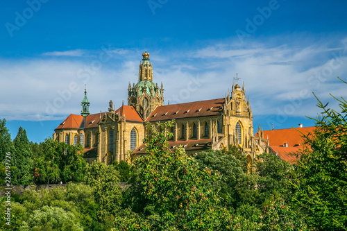 Monumental monastery of Benedictines in Kladruby, Czech Republic, Europe from 12th century standing on hill, includes church of All Saints, red roof, green foreground, sunny summer day, blue sky photo
