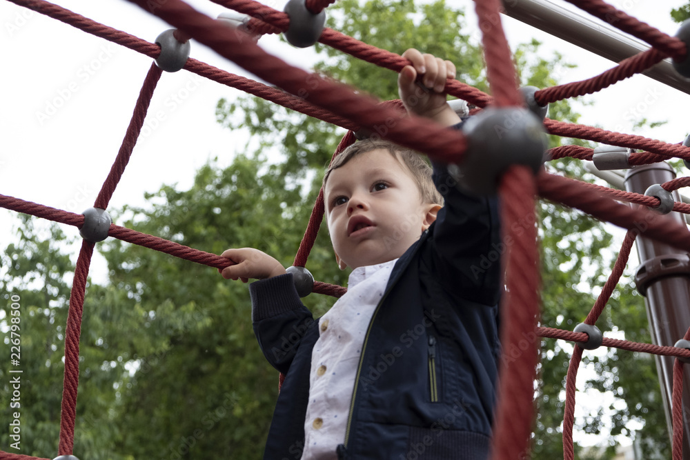 Obraz premium little boy playing in a rope park