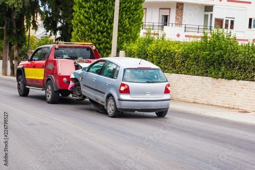 Crashed car being towed away by tow truck after accident