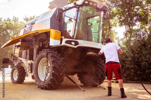 Fotografie The mechanics repair the yellow combine harvester in the farm yard