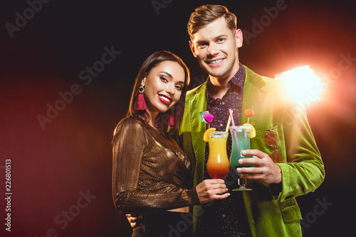 beautiful glamorous couple clinking with cocktail glasses on party with back light