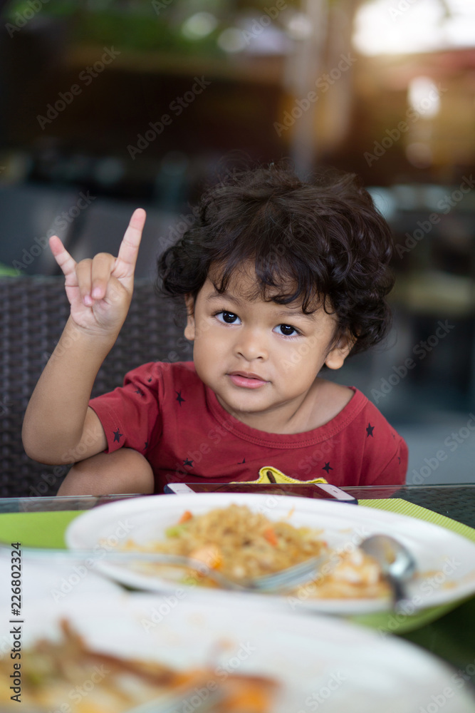 Curly hair asian child eating breakfast in a restaurant Curly hair asian child eating breakfast in a restaurant