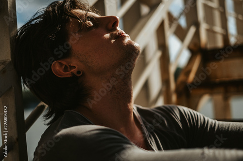 Handsome man sitting on the staircase with eyes closed