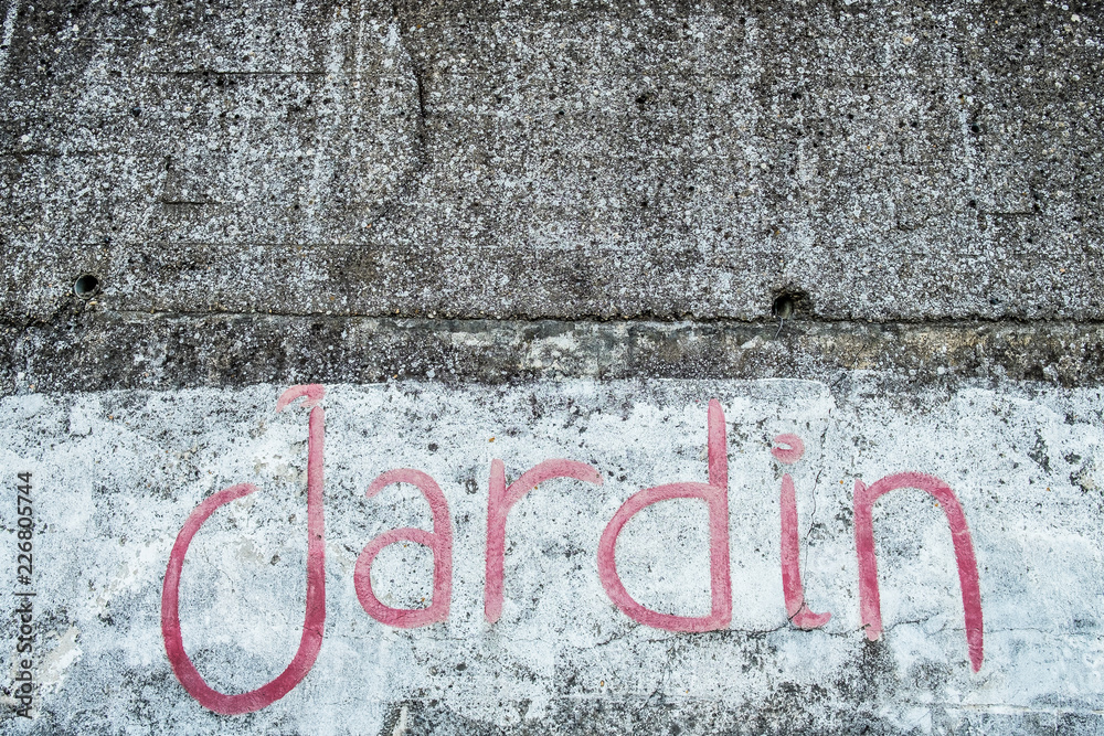 Inscription jardin peinture rouge sur fond béton gris Inscription jardin peinture rouge sur fond béton gris