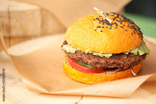 Foto hamburger with a cutlet and tomato in a cafe lies on a wooden board and kraft pa
