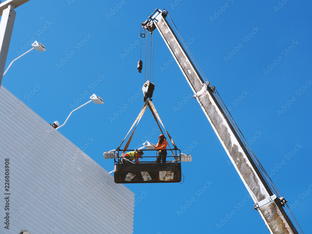 Naklejka premium construction worker at construction site using lifting boom machinery
