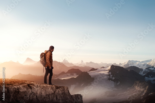Rear view of a man standing on the cliff against sunset Fototapet