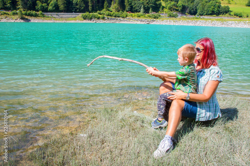 mother and son fishing with a wood in a lake