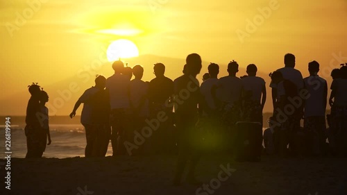 Lucky crowd on a seeshore looking at a huge sun in Vietnam at sunset in slo-mo photo