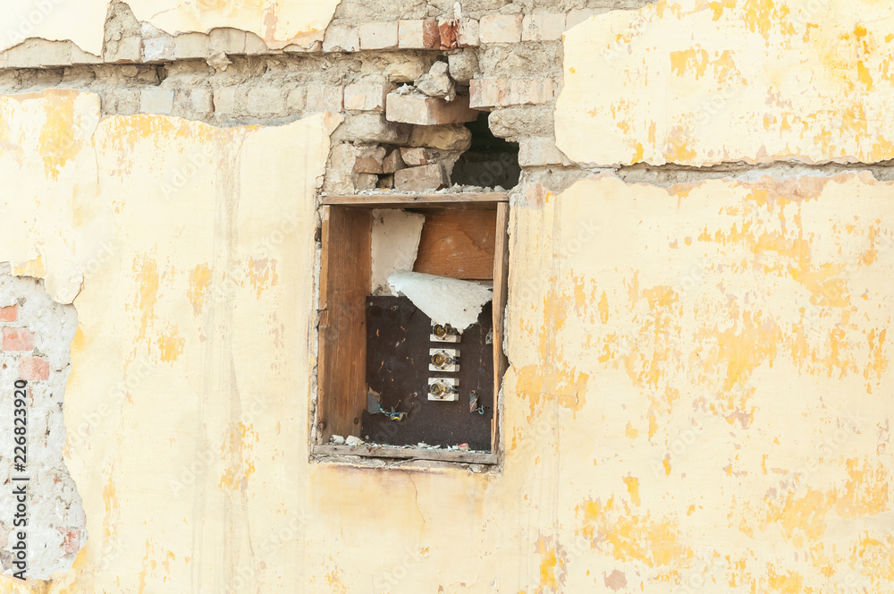 Broken and damaged electric fuse box on demolished house in the war conflict zone